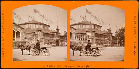 Suomen ensimmäinen yleinen taide- ja teollisuusnäyttely vuonna 1876 Kaivopuistossa. Theodor Höijerin suunnittelemaa näyttelyrakennusta Kaivohuoneen pohjoispuolella mainostettiin julisteessa, joka on säilynyt meidän päiviimme asti. Ajurin hevonen vaikuttaa vierasveriseltä "loistohevoselta", kuten tuohon aikaan tavattiin sanoa. Charles Riisin ottama kuva on Helsingin kaupunginmuseon kokoelmista.